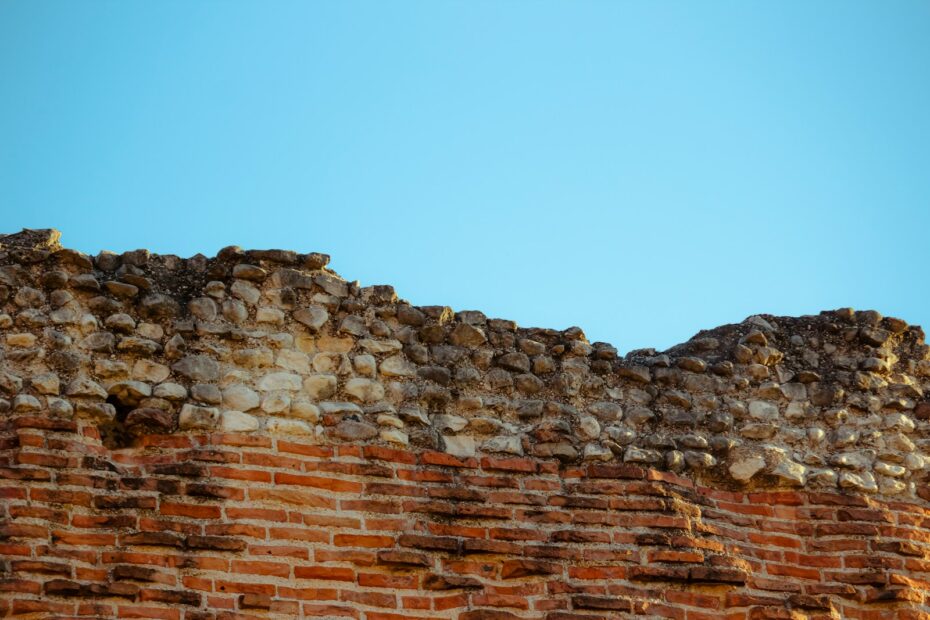 Old brick wall stands against a clear blue sky.