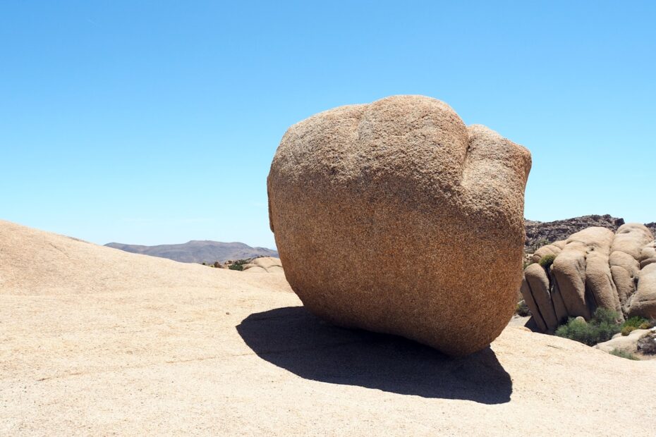 Large boulder casting a shadow on sunny desert landscape