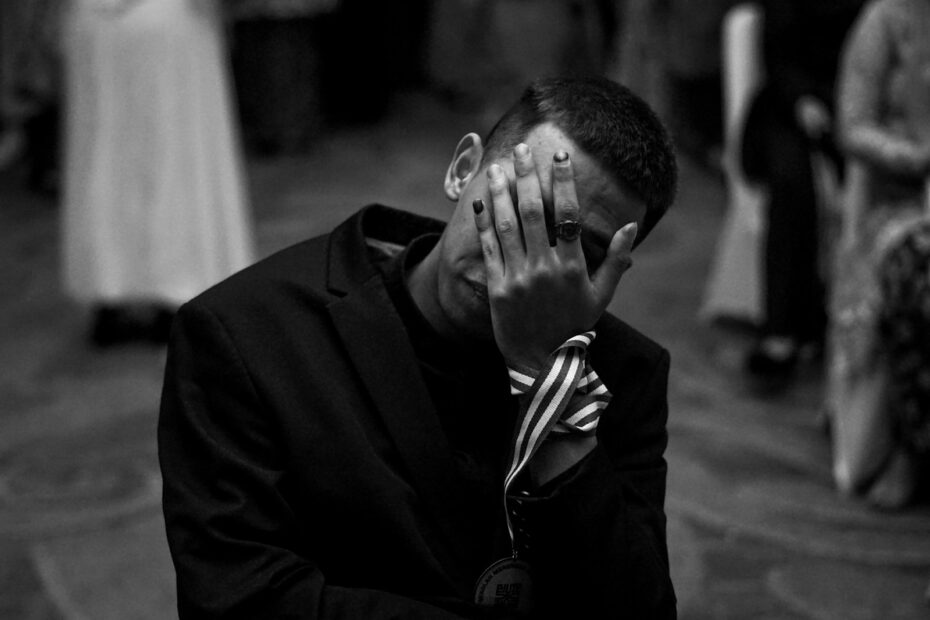 Man in suit covers face with hand